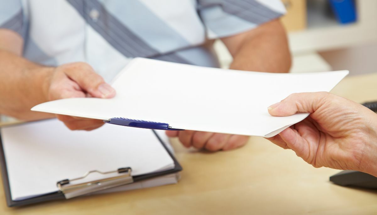 person with a clipboard handing a paper to another person